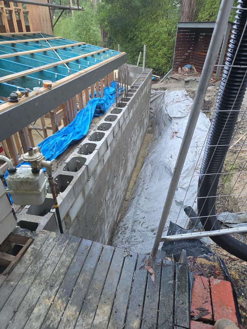 Basement block wall with open cores beside timber floor framing and waterproof membrane, basement blockwork, Melbourne