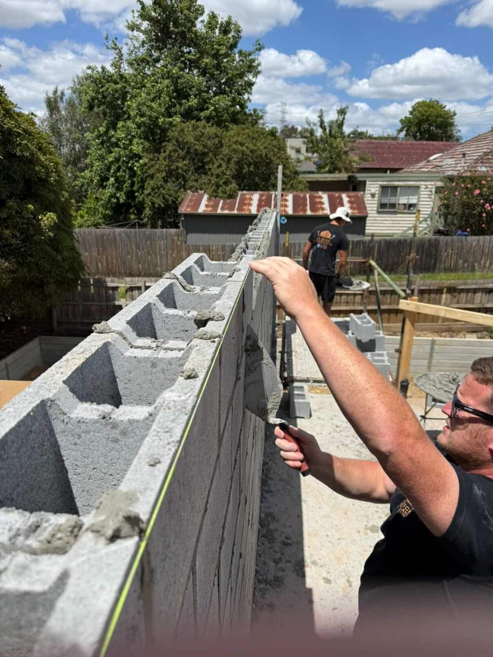 Blocklayer laying a besser block wall with open cores along the top course, blocklaying, Melbourne